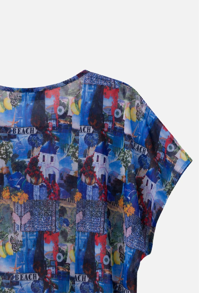 A close-up of the sheer blouse neckline and sleeve, highlighting the Mediterranean collage print. The details of blue and white buildings and fruit are sharp on a white background.